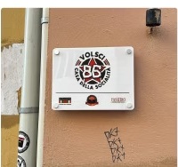 La targa della Casa della Socialità, Volsci 86, sulla parete esterna.